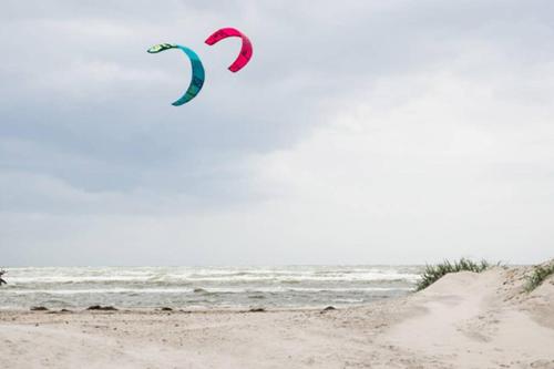 two kites flying over the ocean on a beach at Friluftsstigen Cabin in Falkenberg
