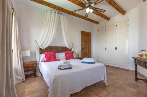 a bedroom with a large white bed with red pillows at Casa el Imperio in Gaucín