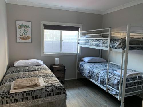 a bedroom with two bunk beds and a window at Laguna lodge in Sussex inlet