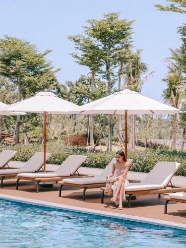 a woman sitting on a chair next to a swimming pool at 1 Hotel Haitang Bay, Sanya in Sanya