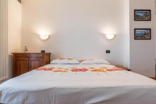 a bedroom with a large white bed with flowers on it at Baita Serpillo in Palù del Fersina
