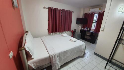 a bedroom with a white bed and red curtains at D.D. Inn Beach Guesthouse in Pattaya South