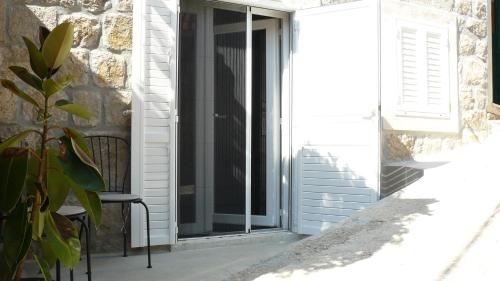 a glass door with a chair next to a building at Eco Apartments Kate in Suđurađ