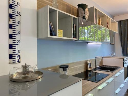 une cuisine avec des armoires blanches et un mur bleu dans l'établissement Bel Appartement - Brive Centre - Quartier Musée, à Brive-la-Gaillarde