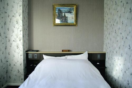 a bedroom with a white bed and a picture on the wall at Mizno Hotel in Fujikawaguchiko