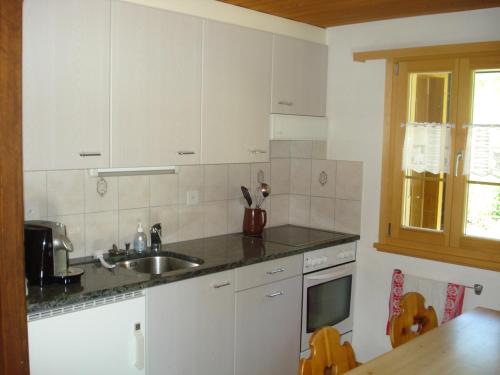 een keuken met witte kasten en een wastafel bij Chalet Erika in Eriz