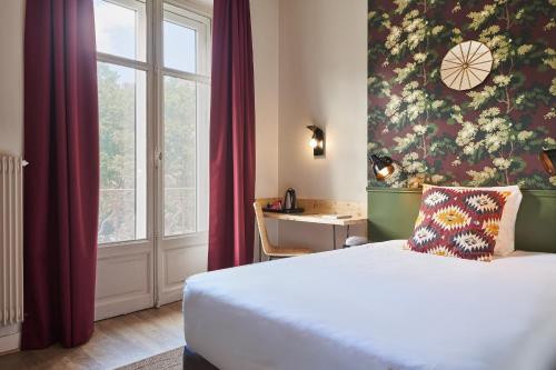 a hotel room with a bed and a window at Hôtel Stanley by HappyCulture in Nancy