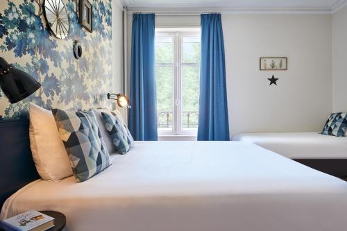 a bedroom with a large bed with blue curtains and a window at Hôtel Stanley by HappyCulture in Nancy