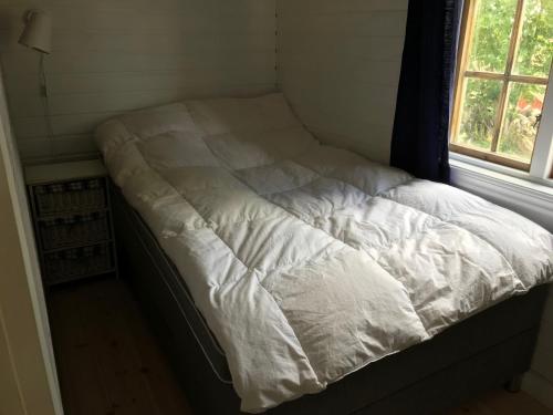 an unmade bed in a small room with a window at Stuga med havsutsikt i Sankt Anna in Sankt Anna