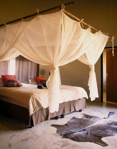 a bedroom with a canopy bed with a picture on the floor at Lamai Safari Lodge in Balule Game Reserve
