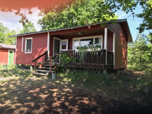 Casa pequeña roja con porche y balcón en Havsutsikt i Sankt Anna en Sankt Anna