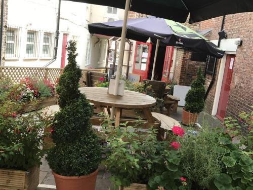 a patio with a table and some plants and an umbrella at Chapter Two Bar in Malton