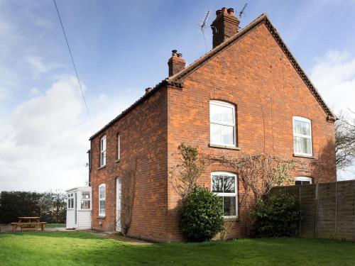 une maison en briques avec une table de pique-nique devant dans l'établissement Dairy Barns Holiday Cottages, à Norwich