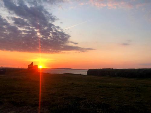 a sunset over a field with the sun in the sky at McMunns of Ballybunion in Ballybunion