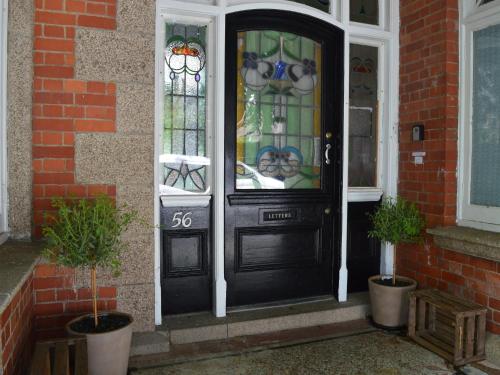 une porte d'entrée noire avec un panneau sur celle-ci dans l'établissement Owl House, à Redruth