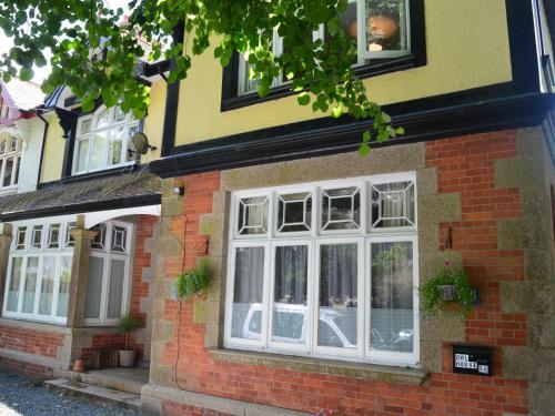 Una casa de ladrillo con ventanas blancas. en Owl House en Redruth