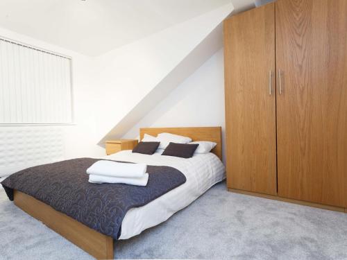 a bedroom with a large bed and a wooden cabinet at Ruth Apartments in Leeds