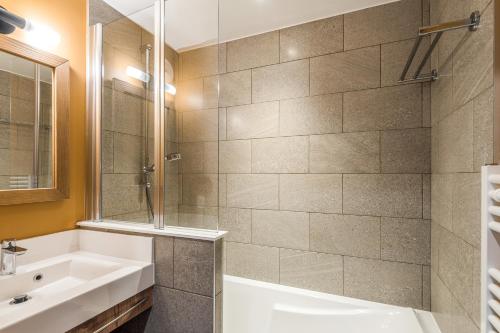 a bathroom with a tub and a sink at Residence Arietis - maeva Home in Avoriaz