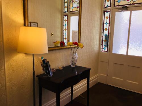 um quarto com uma mesa com um candeeiro e uma janela em Shrubbery Guest House em Worcester