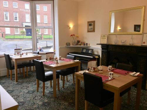 un ristorante con tavoli, pianoforte e specchio di Shrubbery Guest House a Worcester