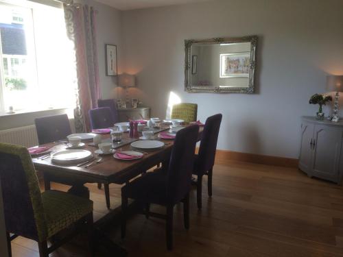 a dining room table with chairs and a mirror at The Barn At Woodview in Hildenborough
