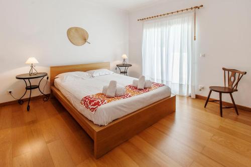 a bedroom with a large bed with two chairs at Quinta do Peru I in Quinta do Conde