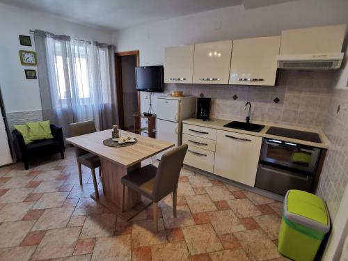 a kitchen with a table and chairs and a kitchen with white cabinets at Apartments Emili in Dajla