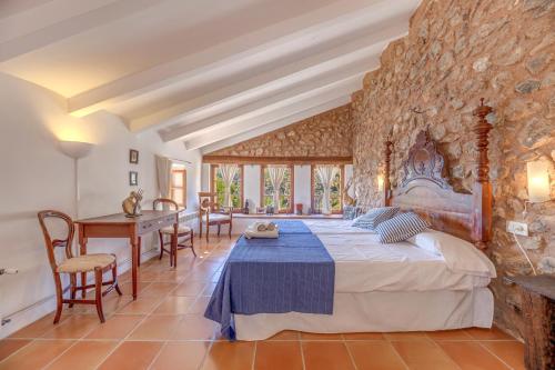 a bedroom with a large bed and a stone wall at Sa Cabana Vella Fornalutx in Fornalutx