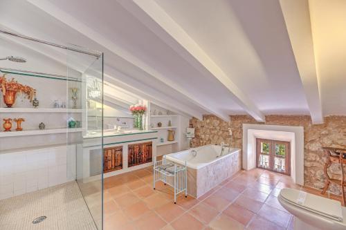 a bathroom with a tub and a glass shower at Sa Cabana Vella Fornalutx in Fornalutx