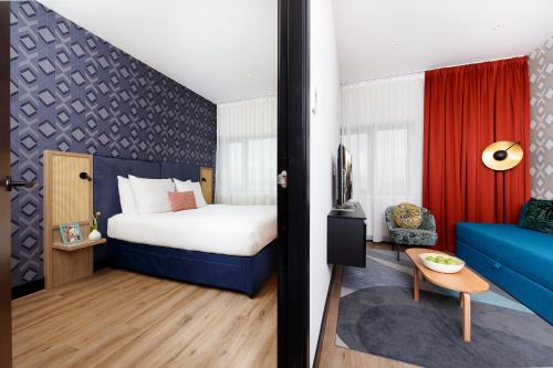 um quarto de hotel com uma cama e um sofá azul em Citadines Sloterdijk Station Amsterdam em Amesterdão