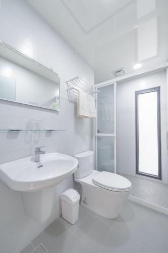 a white bathroom with a toilet and a sink at 聽故事台南民宿 有貓的民宿 in Tainan