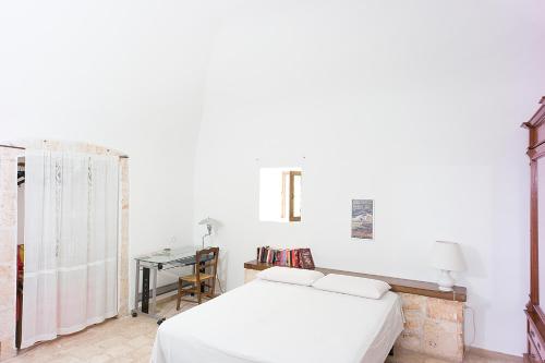 Dormitorio blanco con cama y mesa en Depéndance, en Polignano a Mare