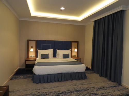 a bedroom with a large bed with a blue headboard at Swiss Blue Al Samer in Jeddah