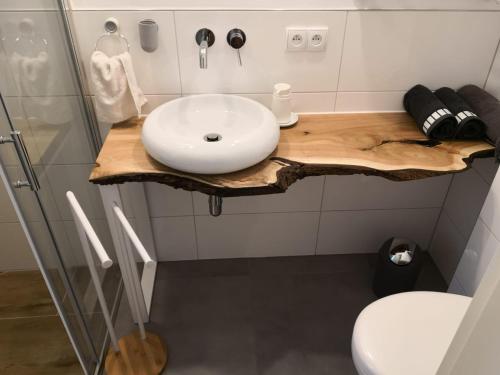 ein Badezimmer mit einem weißen Waschbecken auf einer Holztheke in der Unterkunft Loftowe mieszaknie w okolicach jezior i lasu. in Osowiec Śląski