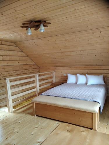 a bedroom with a bed in a wooden cabin at Катерина in Rozhanka Nizhnyaya