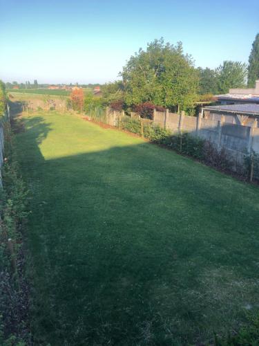 a large yard with green grass and a fence at 't schotje in Ledegem