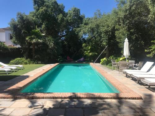 una piscina en un patio con sillas y sombrilla en La Dulcinea, en Sotogrande