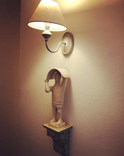 a statue of a woman under a lamp on a wall at La Dimora di San Simplicio in Olbia