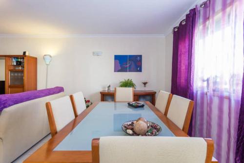 ein Esszimmer mit einem Tisch und lila Vorhängen in der Unterkunft Rooms_Heart Apartment in Faro