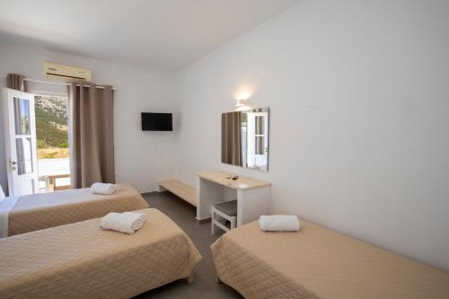 um quarto de hotel com duas camas e uma secretária em Hotel Galini Sifnos em Apollonia
