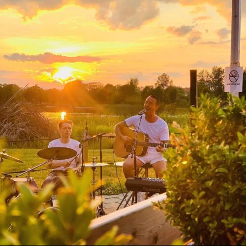two men are playing music at sunset in a field at Hasse på Sjökanten Hotell & Restaurang in Jönköping