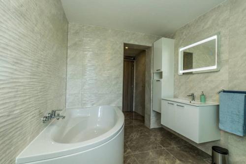 Un baño con bañera blanca y lavabo. en Villa Amaris, en Brodarica