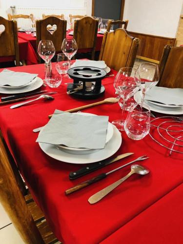 une table avec un tissu de table rouge, des assiettes et des verres à vin dans l'établissement Auberge d+ Valloire-Galibier, à Valloire