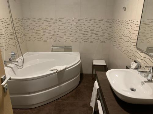 un bagno bianco con vasca e lavandino di Turin Airport Hotel & Residence a San Francesco al Campo