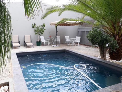 a swimming pool in a yard with a table and chairs at Bateleur Self Catering cc in Windhoek