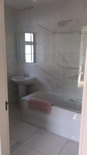 a white bathroom with a tub and a sink at St Anthony's Rosslare Strand in Mervyn