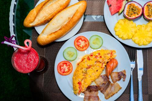 a table with three plates of food with pizza and bread at Green Hill Hotel in Hoi An