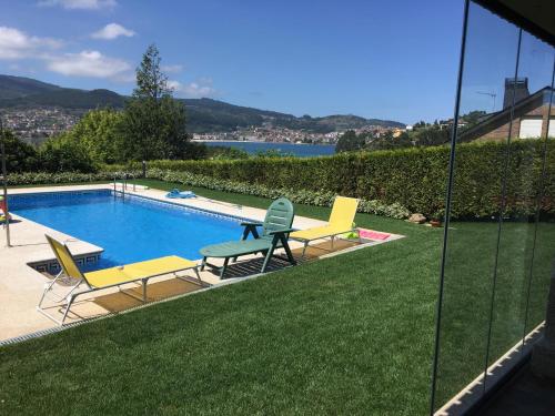 una piscina con 2 sillas de césped y una piscina en Playa America!, en Nigrán
