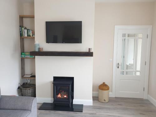 a living room with a fireplace with a tv above it at Barr an Uisce in Achill Sound