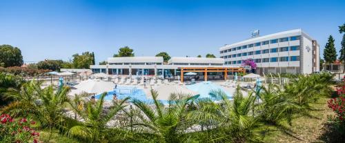 a resort with a pool with umbrellas and a building at Hotel Bolero in Biograd na Moru